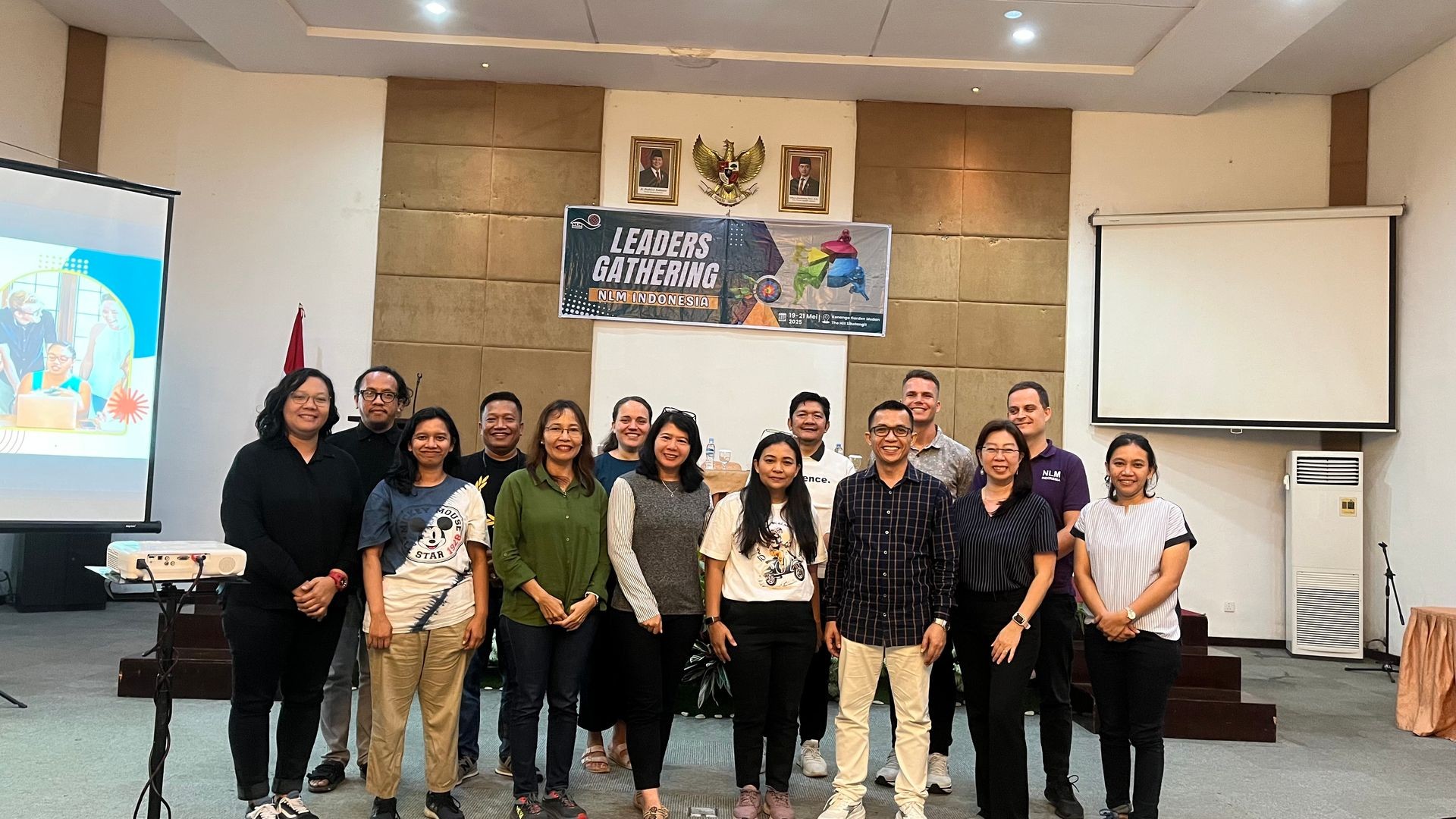 Group of people standing in a room with a 'Leaders Gathering' banner behind them.