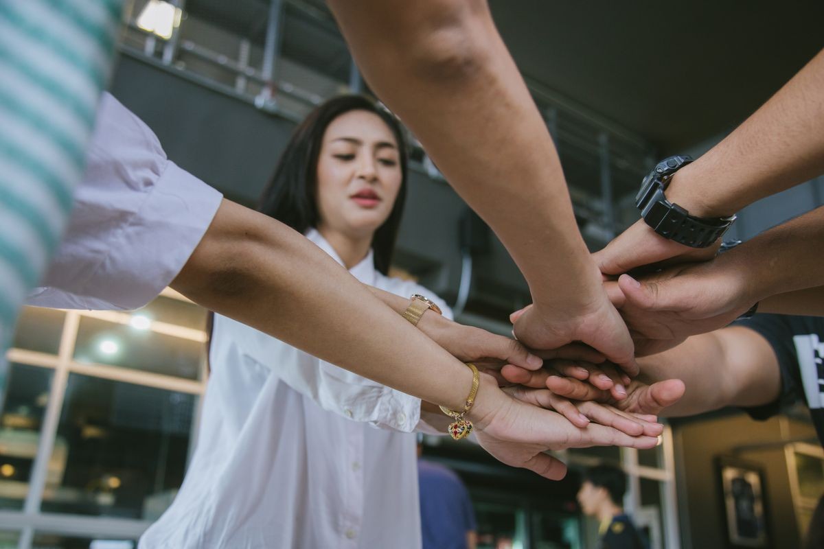 Close up top view of young people putting their hands together. Friends with stack of hands showing unity and teamwork.